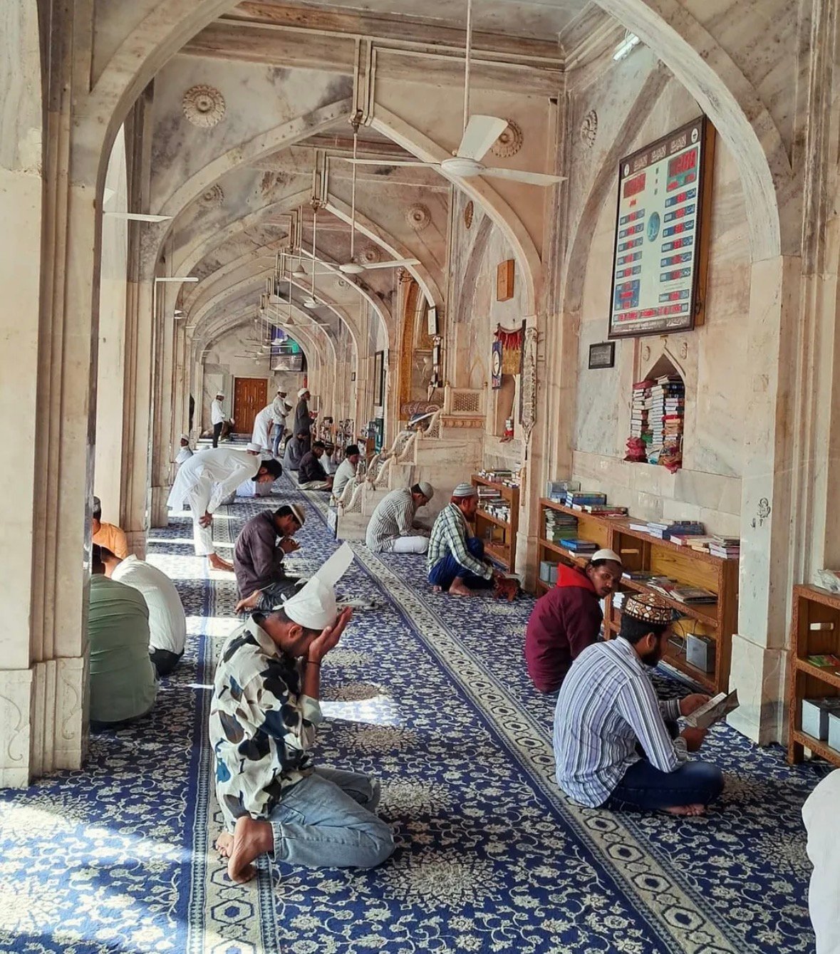 Visitors seated along the arched interior of Shahjahani Masjid