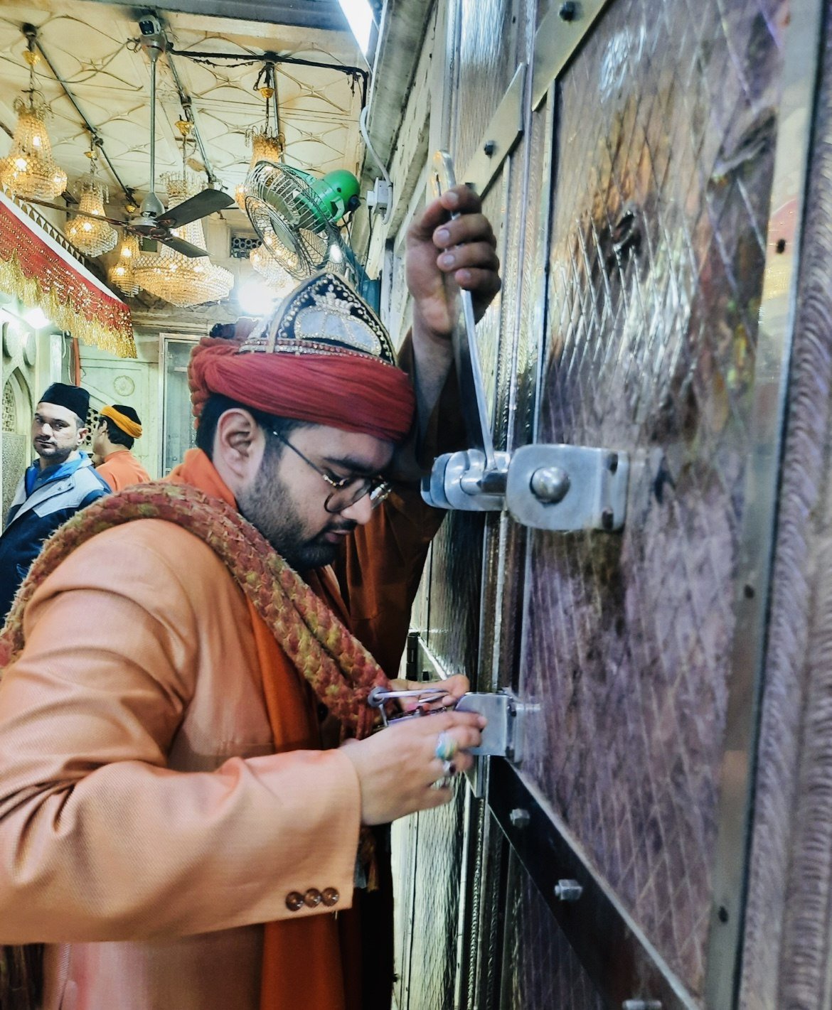Attendant beside a decorated doorway with metal locking fittings
